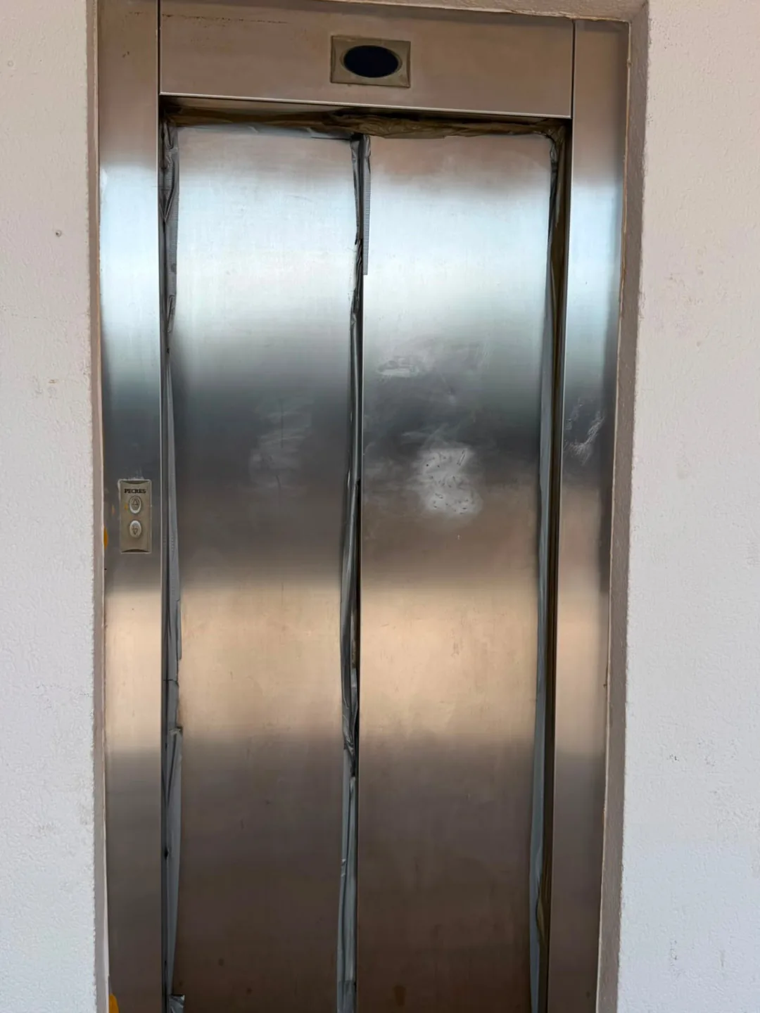 The same stainless-steel lift entrance at Centro Comercial Flamenca Beach after detail cleaning, with the brushed steel finish visible again.