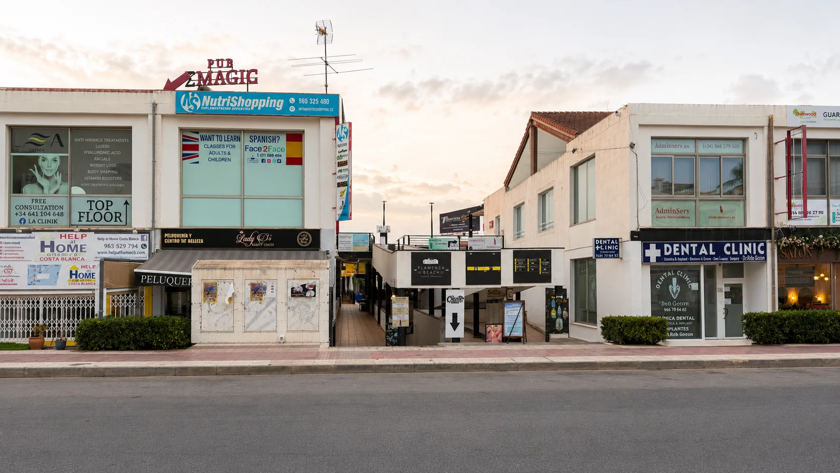 Flamenca Beach Shopping Centre — illuminated retail frontage and main entrance arch at dusk in Orihuela Costa.