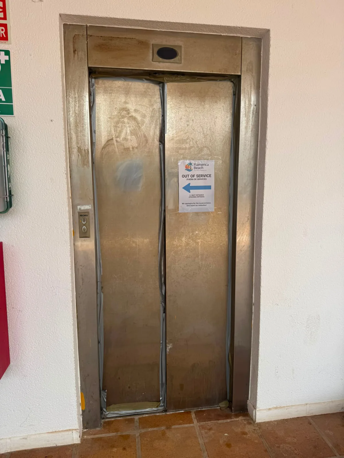 Stainless-steel lift entrance at Centro Comercial Flamenca Beach before detail cleaning, with staining and marks across the door panels and frame.